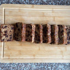 Sliced banana bread on a wooden cutting board with a granite countertop background
