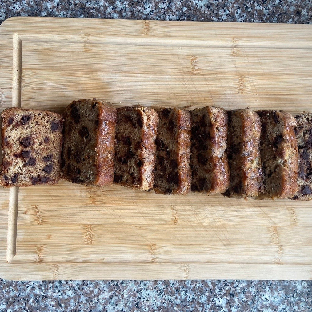 Sliced banana bread on a wooden cutting board with a granite countertop background